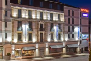 a hotel with a lit up facade at night at Kyriad Hotel Dijon Gare in Dijon