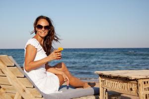 una mujer sentada en una silla en la playa con una bebida en Eldorado Lodge and Restaurant en Dahab