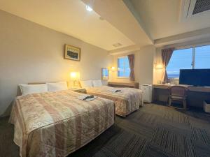 a hotel room with two beds and a flat screen tv at サンホテル大間 in Ōma +33 photos