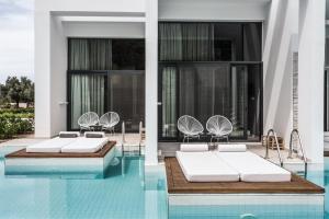 una piscina con 2 camas y sillas en un edificio en Casa Cook Rhodes (Adults Only), en Kolymbia