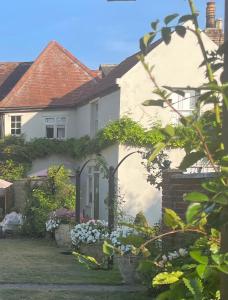 a white house with flowers in the yard at Blythe Cottage in Long Melford