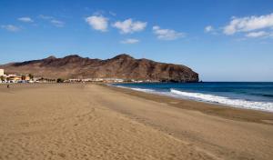 グラン・タラハルにあるApartamento Playa Gran Tarajalの山を背景に広がるビーチの景色