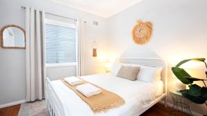 a bedroom with a white bed with two towels on it at Sandy Paws in Culburra Beach