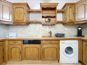 a kitchen with wooden cabinets and a washing machine at Le Luxembourg - Appartement proche des Halles - Wifi in Narbonne