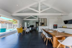 una sala da pranzo con un lungo tavolo in legno e sedie di La villa Sirelis piscine et spa a Gujan-Mestras
