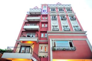 un edificio alto de color rosa con balcones y relojes. en 七星天使-七星潭電梯民宿 en Dahan