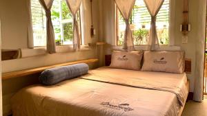 a bedroom with a bed with pillows and windows at Đà Lạt in Phú Quốc Homestay - Free Airport Pickup for 4 night bookings in Phu Quoc