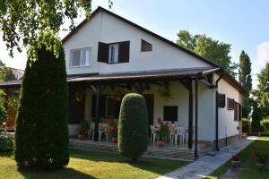 a white house with a porch and some bushes at Rózsa nyaralóház in Balatonboglár