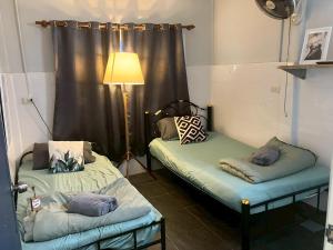 two beds in a room with a lamp and curtains at Cat in the box homestay in Godown