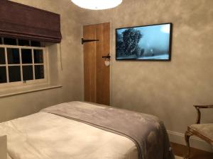 a bedroom with a tv on the wall and a bed at Cosy Barn Conversion - peaceful, private double room in Shenfield