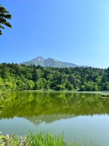 a lake with trees and mountains in the background at Hostel&Bar クツカンタ in Rishiri
