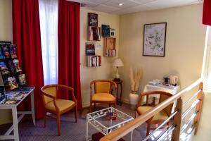 a waiting room with chairs and a table and red curtains at Logis Hôtel Le Pélican & son restaurant in Vernantes