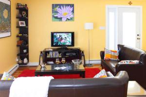 Gite Confort في مدينة كيبك: غرفة معيشة بها أريكة وتلفزيون