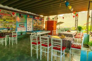 a restaurant with tables and white stools and a table and chairs at Phong Nha Cherish Homestay in Bố Trạch