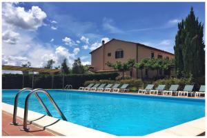 a swimming pool with chairs and a building at Agriturismo La Torricella in Pistoia
