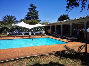 a group of people standing around a swimming pool at Aloe Tree Guest House in Krugersdorp