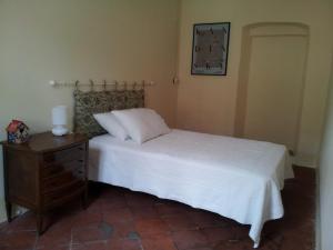 a bedroom with a white bed and a wooden nightstand at Casa Ternavassi in Carmagnola