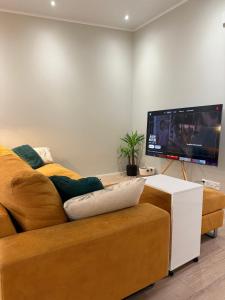 a living room with a couch and a flat screen tv at Rakkamaja Modern Forest-View Apartment in Rovaniemi