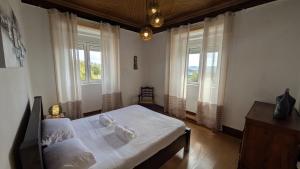 una camera da letto con un letto con lenzuola bianche e finestre di Rei Wamba Apartamento a Vila Velha de Ródão