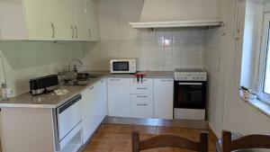 una cucina con armadietti bianchi ed elettrodomestici bianchi di Rei Wamba Apartamento a Vila Velha de Ródão