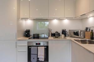 a kitchen with white cabinets and a stove top oven at Stylish 2BR Apartment at Trinity Point Gravesend in Gravesend +30 photos