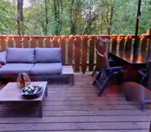 a deck with a couch and a table and lights at Boshuis Nos Bohio Durbuy in Durbuy