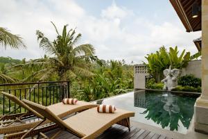 a balcony with chairs and a pool and a statue at Yanyan Resort Ubud in Ubud