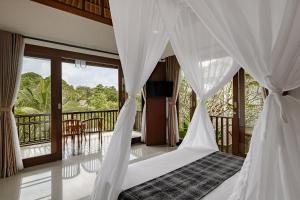 a bedroom with a bed with white curtains and a balcony at Yanyan Resort Ubud in Ubud
