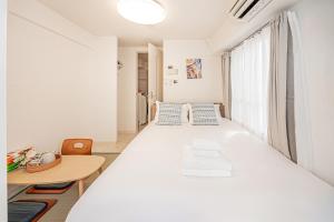una camera da letto con un grande letto bianco e un tavolo di Japan House Shirokane a Tokyo