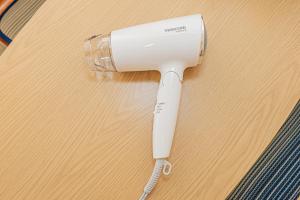 un asciugacapelli elettrico bianco su un tavolo di legno di Japan House Shirokane a Tokyo