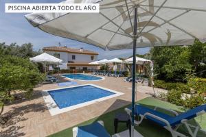 a resort with a swimming pool and an umbrella at Hostal y Apartamento Rural Los Naranjos in Melegis