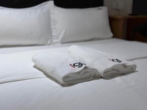 スバン・ジャヤにあるI Go Hotel USJの白いベッドにタオル2枚が備わります。
