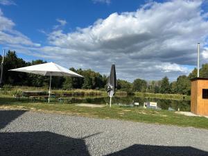 a picnic table with an umbrella next to a lake at Ferien- & Monteurswohnung Krüger Werra Suhl Tal in Raßdorf