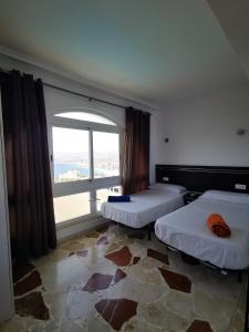 a room with two beds and a large window at Villa Hawai in Benidorm