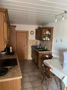 a kitchen with wooden cabinets and a table with chairs at Ferien- & Monteurswohnung Krüger Werra Suhl Tal in Raßdorf +9 photos