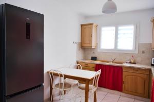 a kitchen with a table and a black refrigerator at Family house with beautiful garden in Saint-Hippolyte
