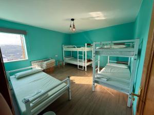 a room with three bunk beds and a window at ALBERGUE Pasiño A Pasiño in Portomarin
