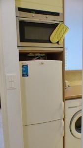 Apartment of 36 m2 with terrace في ساناري سور مير: ثلاجة بيضاء في مطبخ مع ميكروويف