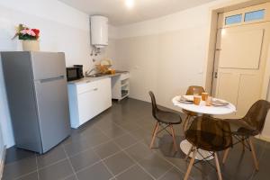a small kitchen with a table and a refrigerator at Casa Histórica T2 no Centro de Vila de Cinfães in Cinfães +16 photos