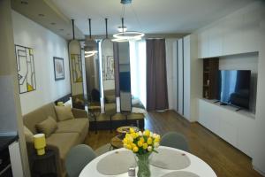 a living room with a couch and a table with flowers on it at Urban Elegance Studio & SPA in Niš