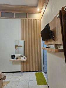 a living room with a television and a green rug at Merapi Indah Hostel in Triwung +2 photos