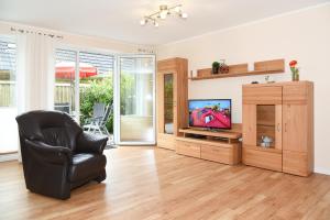 a living room with a black chair and a television at Ferienhaus Wormser Tor - Uns Huus an t Küst in Bensersiel