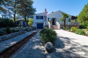 a white house with a stone driveway at House Bianca with garden in Malinska