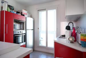 a kitchen with red cabinets and a white refrigerator at Le Remarquable à Saint Martin d'Hères - Situé au Calme - Proche de Grenoble et du Campus - 1 Lit King Size - Climatisation - Balcon - Parking gratuit - Vue montagne in Saint-Martin-dʼHères