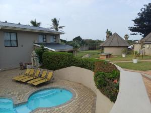 Un patio trasero con piscina y una casa. en Banana Beach Club - C10, en Port Shepstone