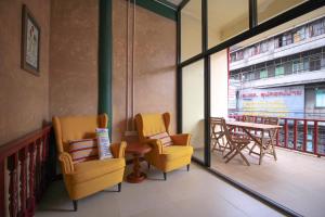 a room with two chairs and a table and a balcony at The Open House Cafe and Hostel in Bangkok