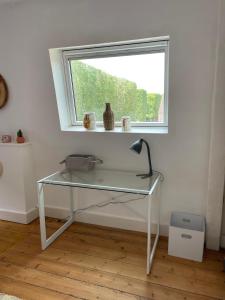 a glass desk with a lamp in front of a window at Chambres dans maison de centre ville in Douai +11 photos