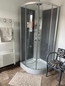 a glass shower in a room with a chair at Chambres dans maison de centre ville in Douai