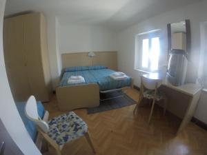 a small bedroom with a bed and a television at Albergo La Caravella in Staranzano