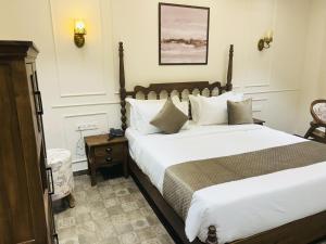 a bedroom with a large bed with white sheets at Amico Inn in Ahmedabad +4 photos